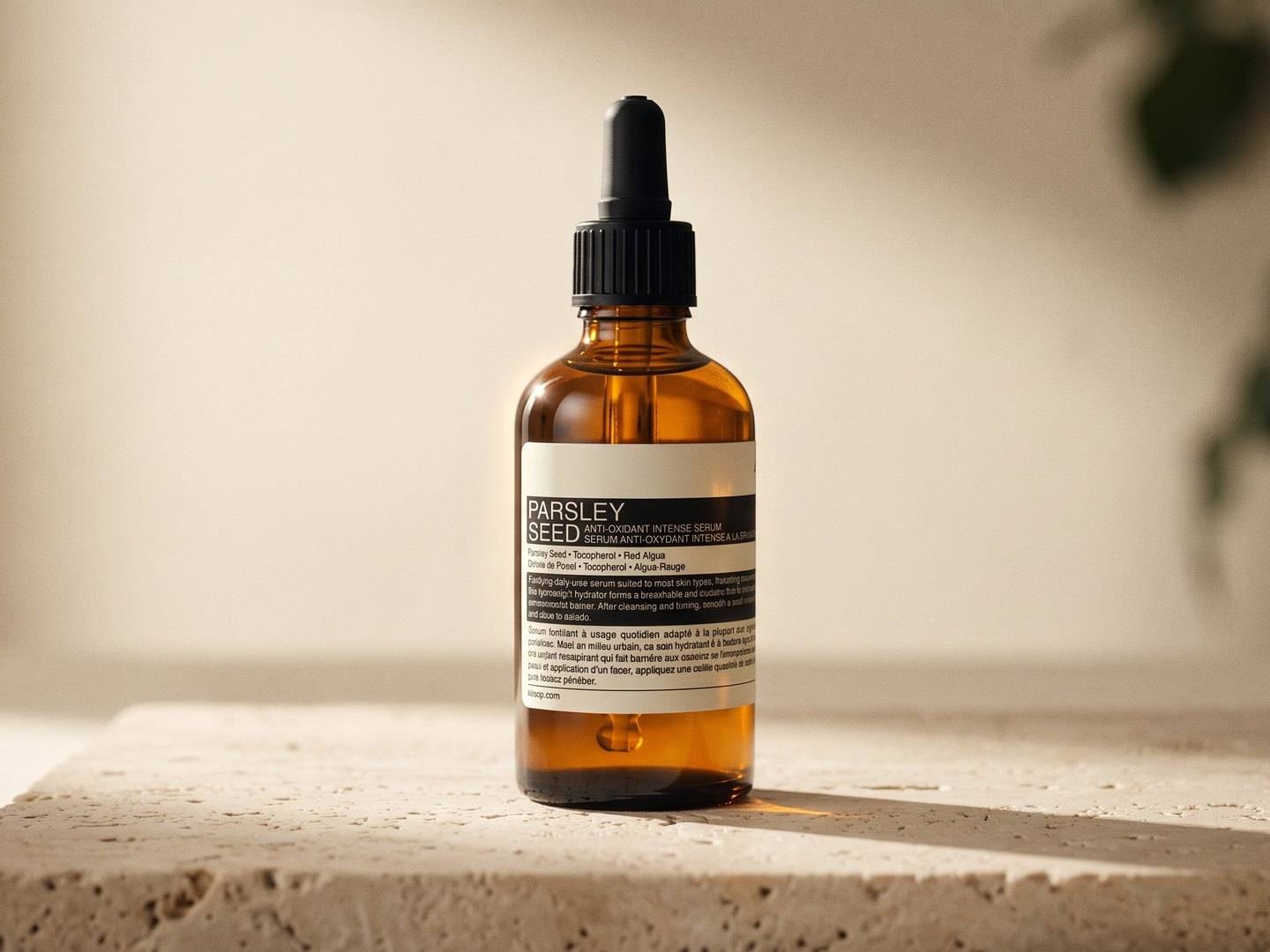 An amber Parsley Seed bottle on a travertine block in warm side light