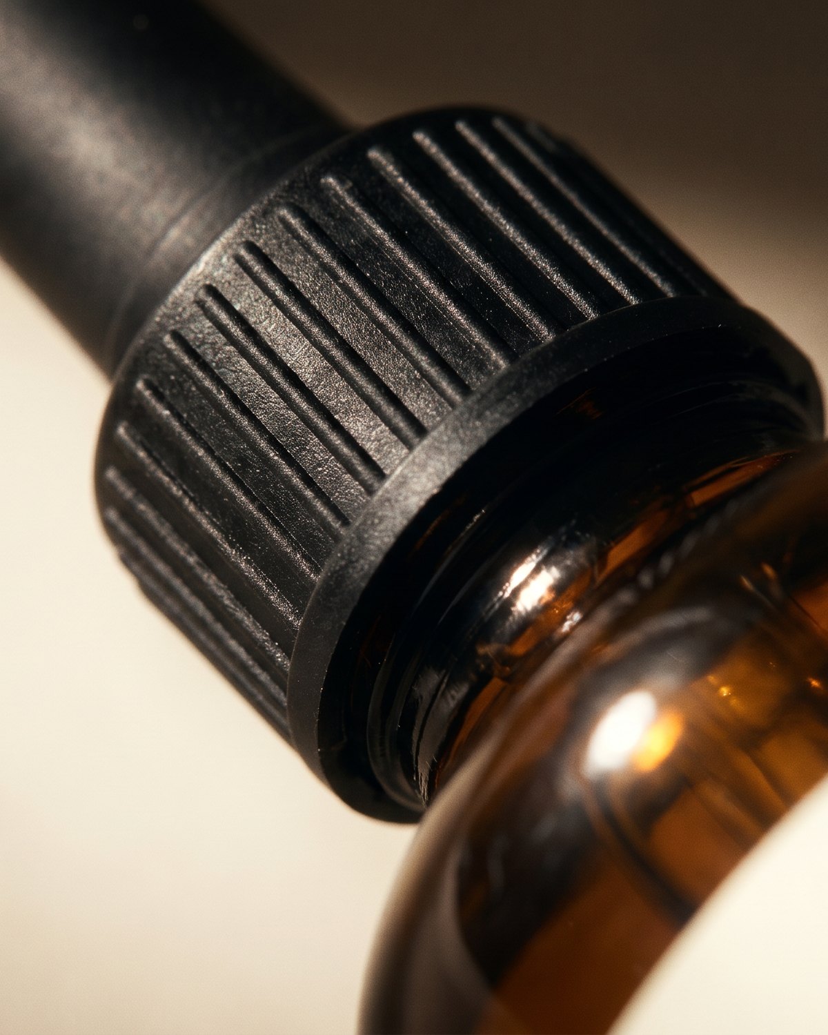 Close detail of the ribbed black dropper cap on amber glass