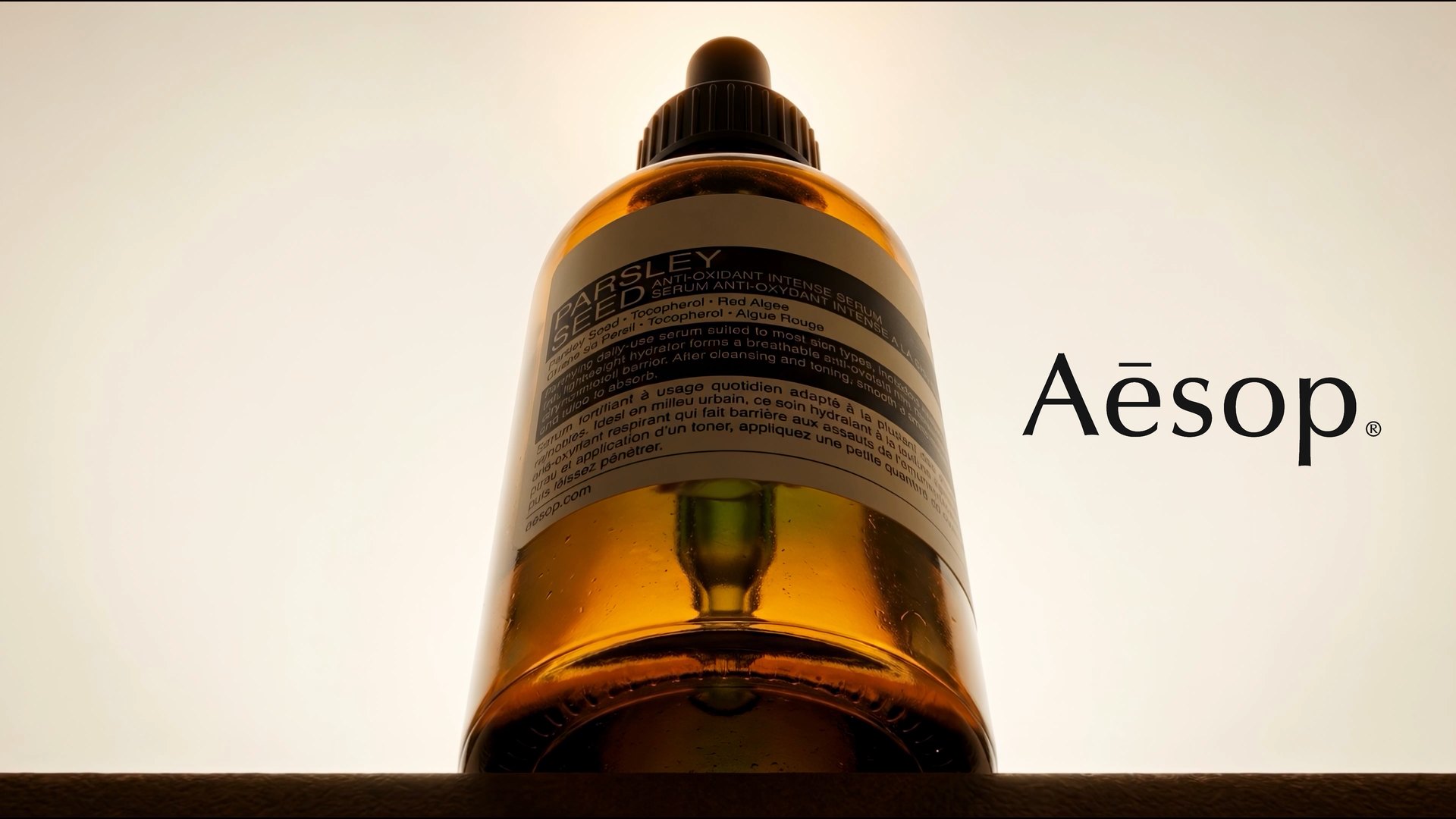 The bottle from below against a pale wall, with the Aesop wordmark